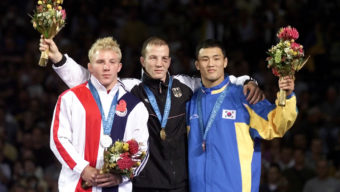 Brandon Slay, left, holding his silver medal for the 76 kg free style wrestling classification, joins with gold medal winner Leipold Alexander, of Germany and bronze medal winner Eui Jae Moon, of Korea for the medals presentations at the Olympics in Sydney, Saturday, Sept. 30,2000. (AP Photo/J.Pat Carter)
